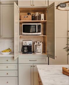 an open cabinet in a kitchen filled with appliances and fruit on the counter top next to a coffee maker