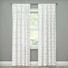 a white curtain hanging on the side of a window next to a wooden floor in front of a gray wall