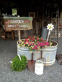 a garden sign sitting on top of a barrel filled with flowers