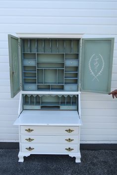 an old dresser has been painted white and is being held up by someone's hand