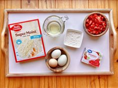 ingredients to make strawberry muffins laid out on a tray with milk, eggs and yogurt