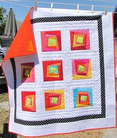 a quilt hanging on a clothes line with an orange top