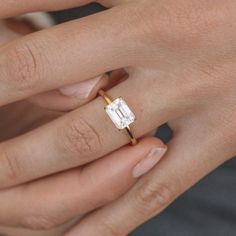 a woman's hand with a diamond ring on her left hand and the other hand holding an engagement ring