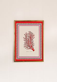 a red and blue coral print hangs on the wall next to a potted plant