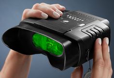 a hand holding a green light in front of a black object with two hands on it