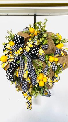 a yellow and black wreath with lemons, greenery and burlap bow