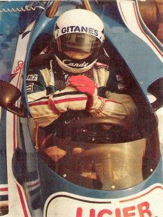 a man sitting in a racing car with his hand on the steering wheel and wearing gloves