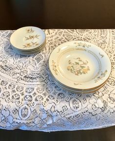 three plates on top of a table covered in white doily with gold trimmings