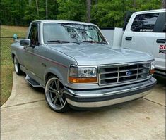 a silver truck parked next to another white truck