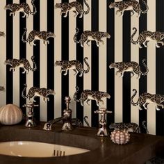 a bathroom with black and white striped wallpaper, leopard print on the walls and a sink