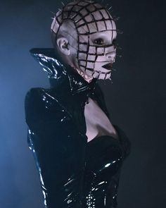 a woman in a black latex outfit with spikes on her head