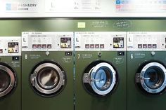 four washers lined up in front of each other with the doors open and buttons on them