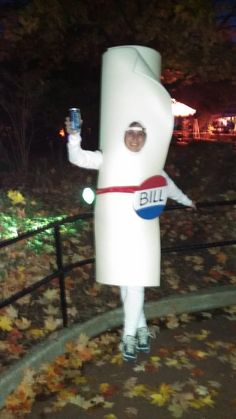 a person in a costume is holding a cell phone and standing on a path with leaves all around