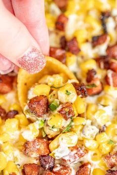 a hand holding a tortilla filled with corn and cheese