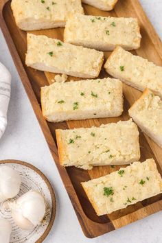 garlic bread on a cutting board next to garlic and garlic cloves, ready to be eaten