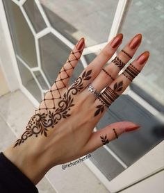 a woman's hand with hennap tattoos on her fingers and wrist,