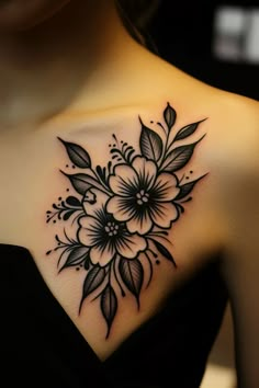 black and white flower tattoo on the back of a woman's shoulder, with leaves