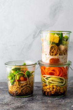 three glass containers filled with food sitting on top of a stone counter next to each other