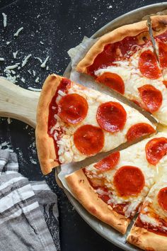 a pepperoni pizza cut into slices on top of a pan with a wooden spatula