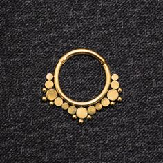 a gold nose ring with small dots on the outside, and an open circle in the middle