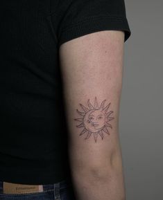 a woman's arm with a small sun and moon tattoo on the left upper arm