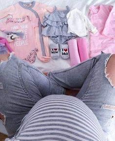 a woman laying on top of a bed next to clothes and toys in front of her