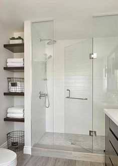 a bathroom with a walk in shower next to a white toilet and wooden flooring