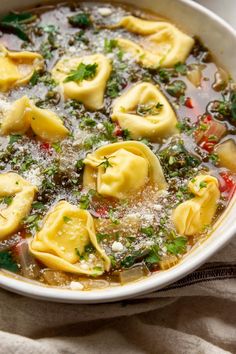 a white bowl filled with dumplings covered in broth and parmesan cheese