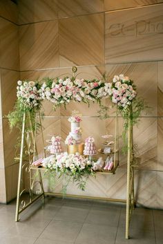 a table topped with lots of cakes and cupcakes on top of a metal stand