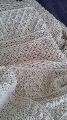 a white crocheted blanket laying on top of a bed