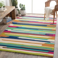 a brightly colored area rug in a living room with a chair and potted plant