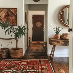 a hallway with rugs, baskets and plants on the floor in front of a door