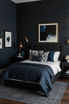 a bedroom with dark blue walls and white bedding, black headboard and foot board