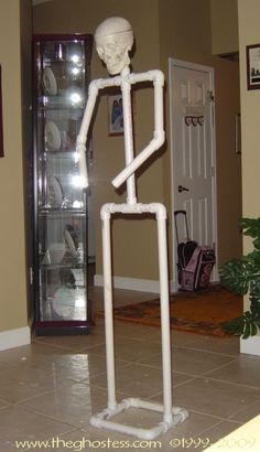 a skeleton is standing in the middle of a room with a glass case behind it