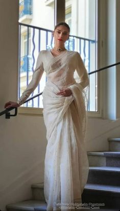 a woman in a white sari standing on some stairs