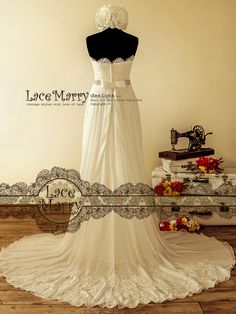 a white wedding dress on display in front of a table with flowers and an old sewing machine