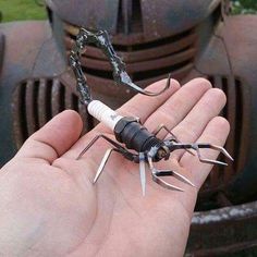 a hand holding a small spider made out of pliers