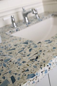 a bathroom sink with blue and white speckles on the counter top next to a faucet