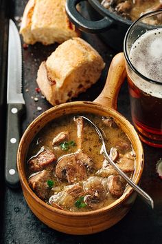 a wooden bowl filled with soup next to bread