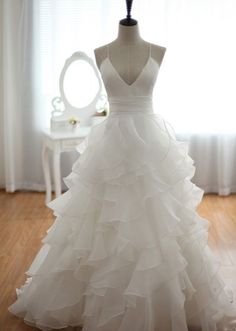 a white wedding dress sitting on top of a mannequin in front of a window