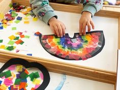 a young child is making a paper plate art project with construction paper and colored shapes