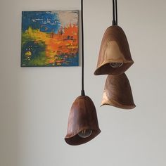 two wooden bells hanging from a ceiling in a room with paintings on the wall behind them