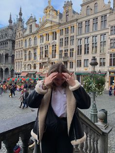 a woman covering her eyes while standing in front of buildings