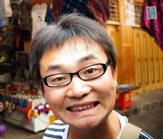 a man wearing glasses standing in front of a store