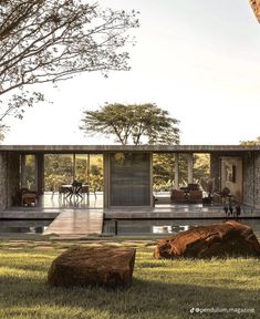 the house is surrounded by large rocks and grass, with an outdoor dining area in the foreground