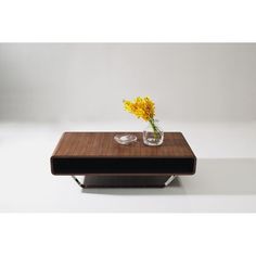 a wooden table topped with a glass vase filled with yellow flowers on top of it