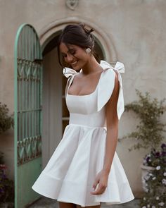 a woman in a short white dress is smiling