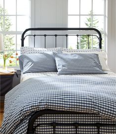 a bed with gingham sheets and pillows in a bedroom next to a window