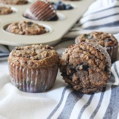 two muffins sitting on top of a blue and white towel next to a cupcake tin