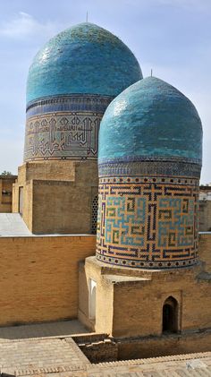 two blue domed buildings with intricate designs on the top and bottom, in an old city